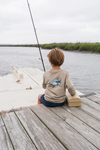 Child sitting on a dock fishing with a shirt featuring a shark design. shark, polo, tee. t-shirt. southern. boy. boys 