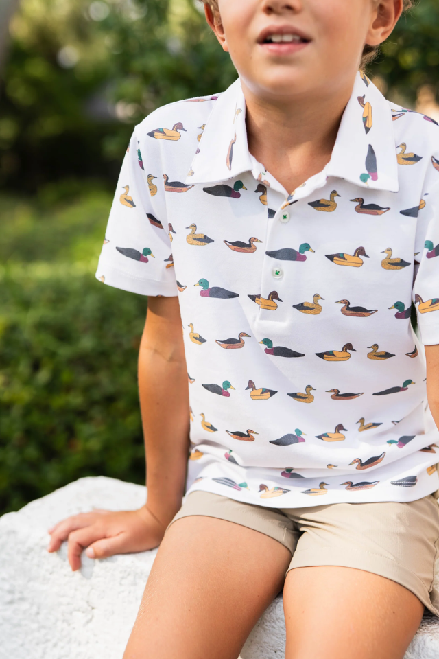 Child wearing a white polo shirt with duck pattern outdoors. mallards. boys polo. polo. boy. outdoors. outdoor