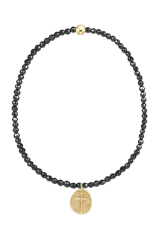 Black beaded necklace with a gold cross pendant on a white background. gold. silver. enewton. tarnishfree. metallic. stackable. bracelets.