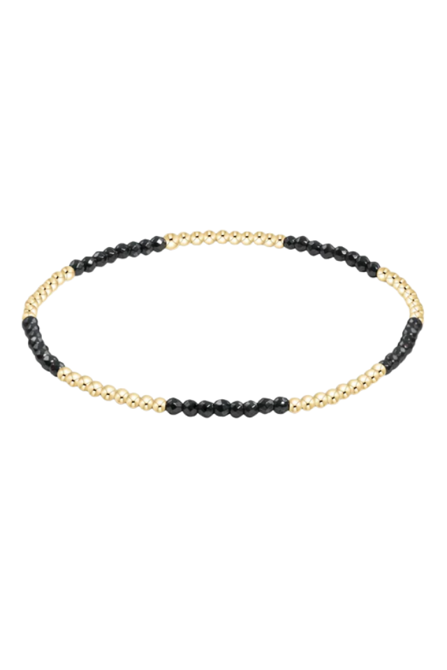 Bracelet with black beads and gold chain on a white background. gold. silver. enewton. tarnishfree. metallic. stackable. bracelets.